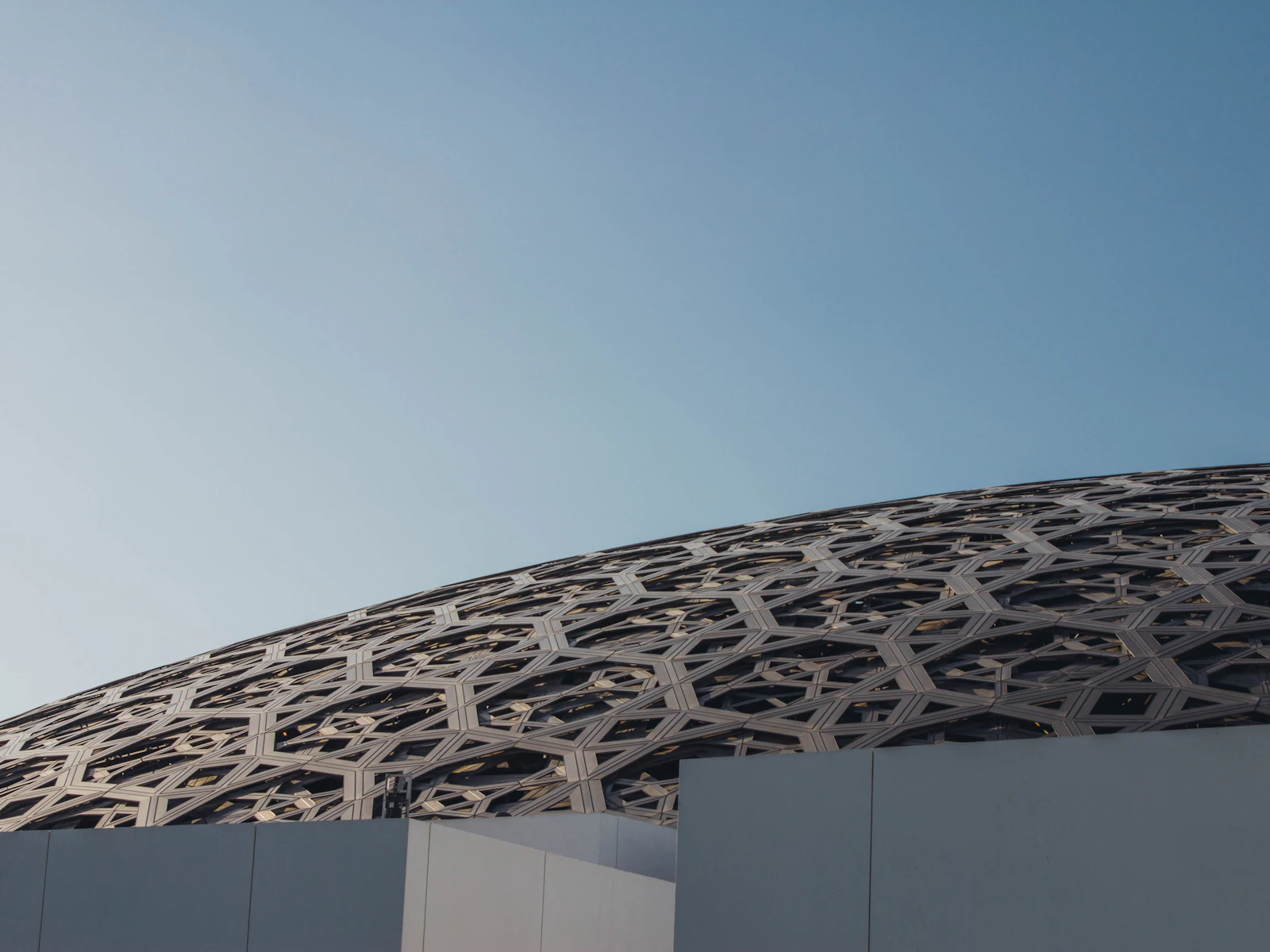The latticed dome of a modern Abu Dhabi landmark against a clear sky