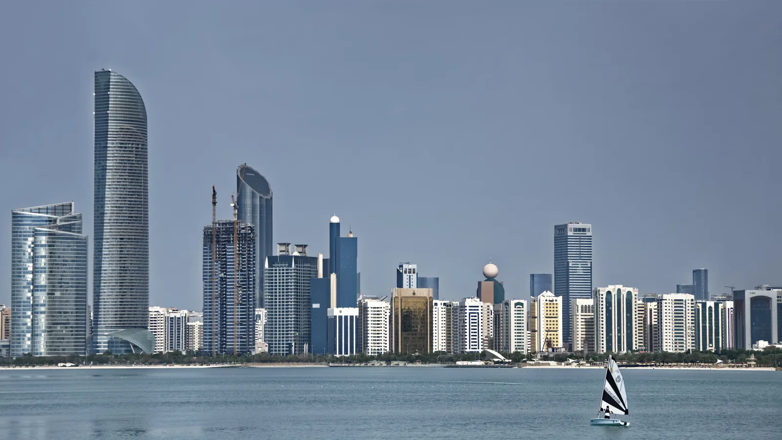 The Abu Dhabi skyline across the water, with a sailboat in the foreground