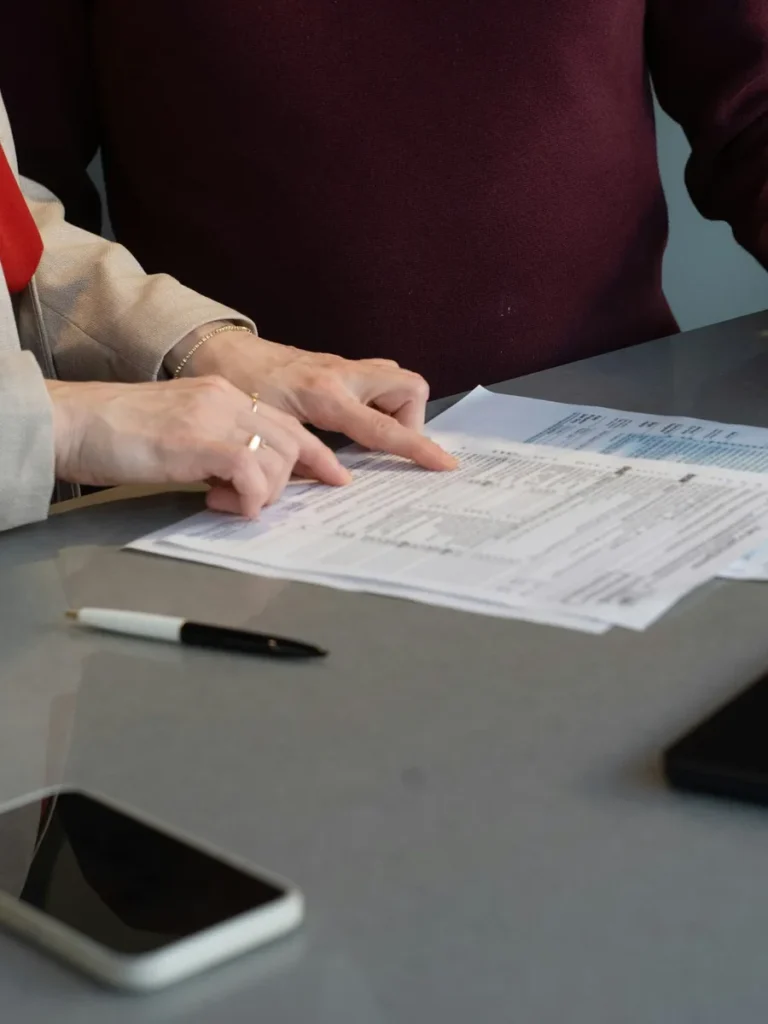 Hands going through a printed compliance form at a meeting table