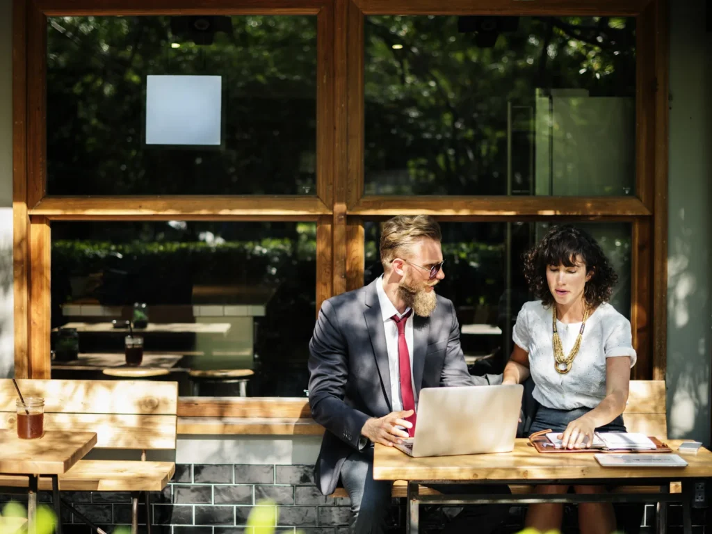 A consultant and a client reviewing work on a laptop at a café table