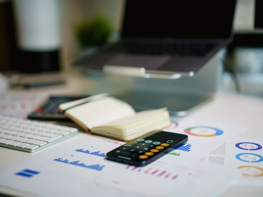 Financial charts, a calculator and a notebook on an office desk