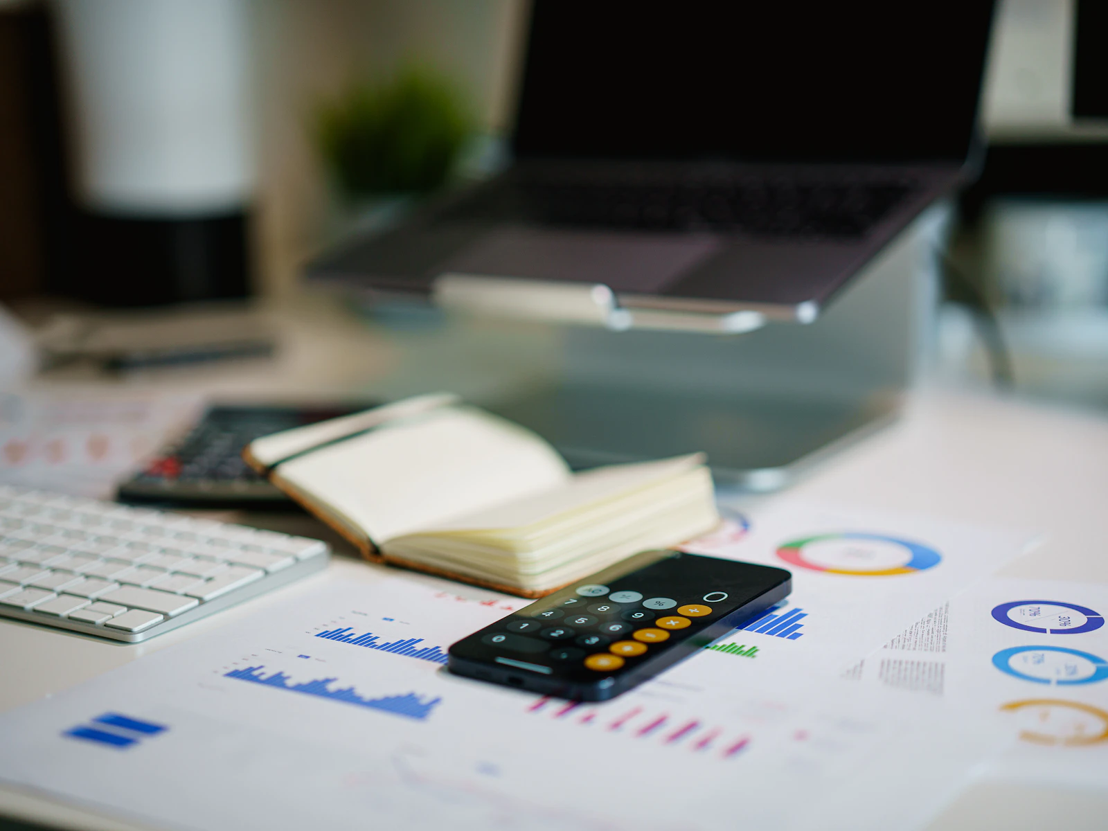 Financial charts, a calculator and a notebook on an office desk