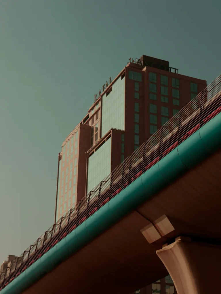 A modern glass and brick building behind an elevated pedestrian bridge