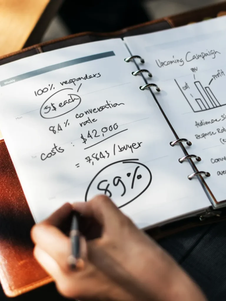 A hand writing figures and a chart into a planner