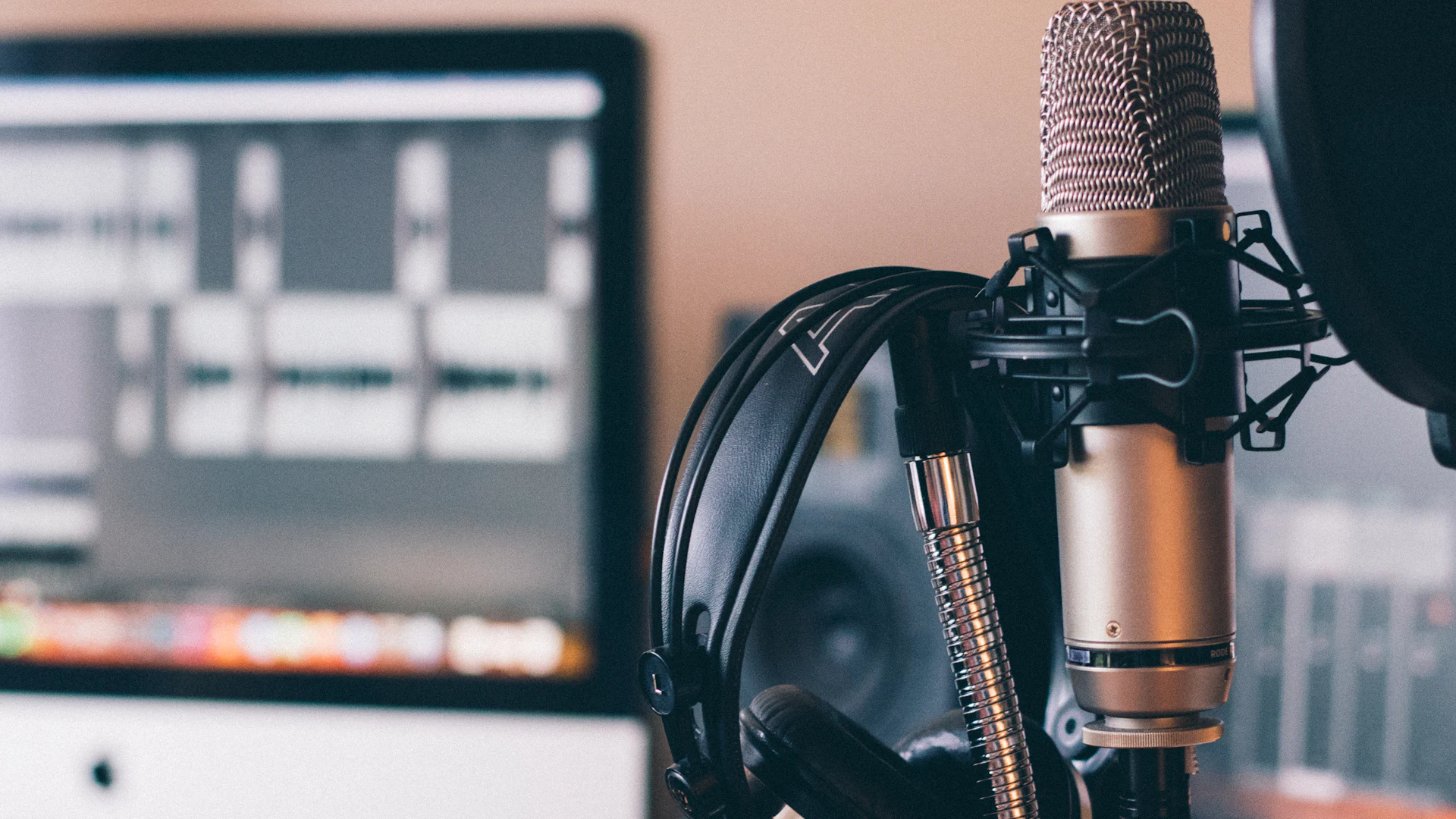 A studio microphone and headphones in front of an editing screen