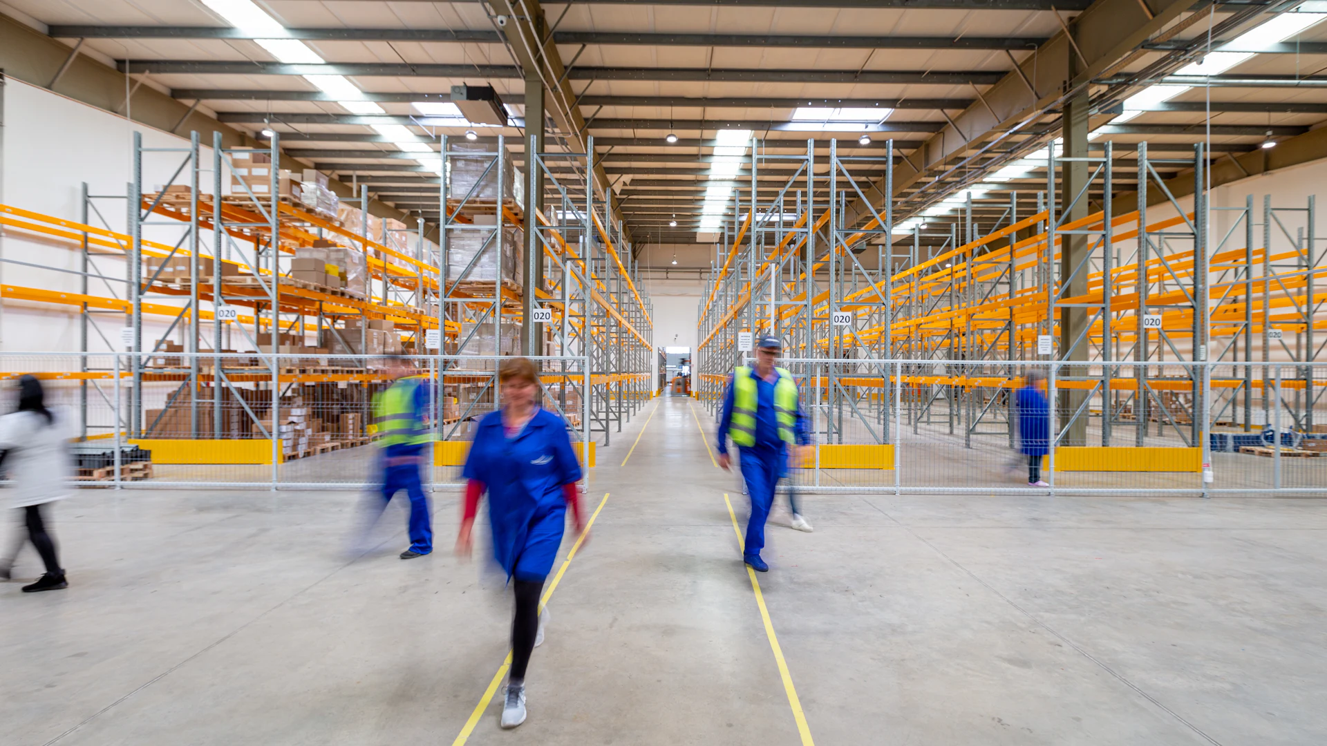 Staff walking a warehouse aisle between storage racking